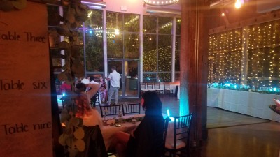 The view of the dance floor/room and glass wall from under the balcony back 10 or 15 feet into other room