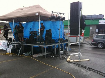 Picture of one stack of 5 Otop112's on scaffolding. Trailer and car in the background. Yamaha 01v in the case in front of the stage